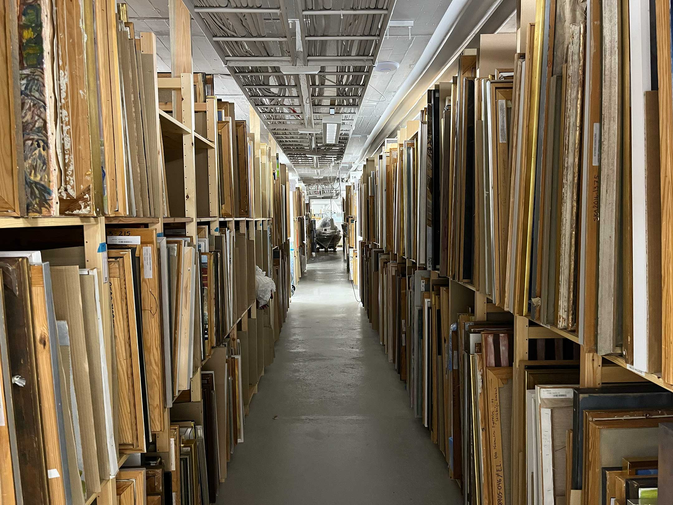 Rows of paintings and framed artworks stored at Statens konstråd collection facility.